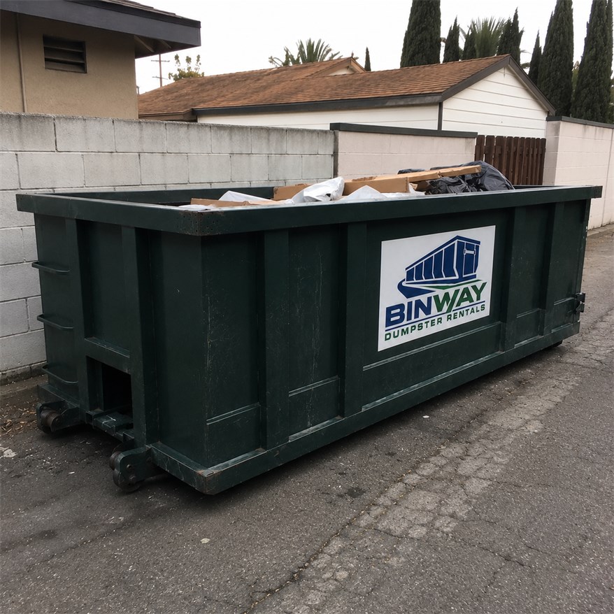 Roll-off dumpster delivered to a back alley and part loaded with cardboard and packing waste